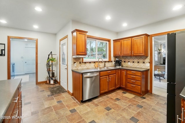 kitchen with brown cabinets, stainless steel appliances, decorative backsplash, and a sink