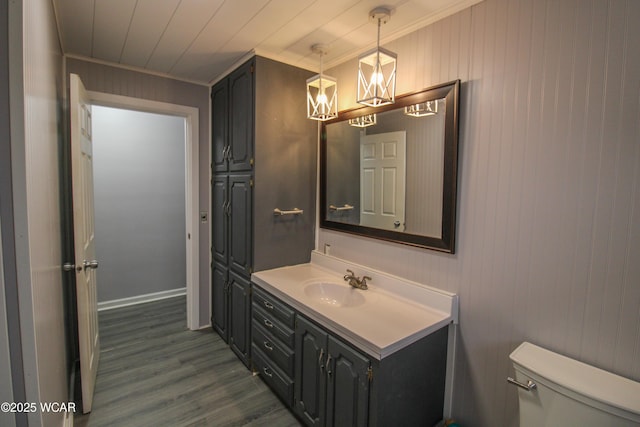 bathroom with hardwood / wood-style flooring, ornamental molding, vanity, and toilet