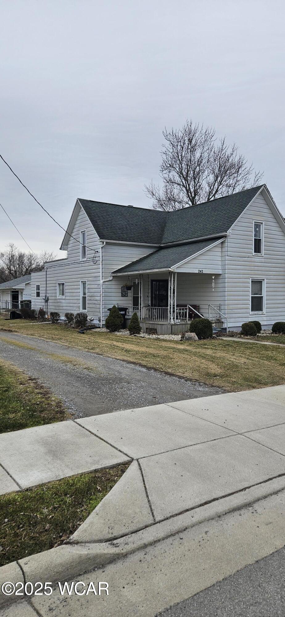 view of front of property featuring covered porch, a front lawn, and roof with shingles