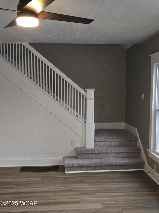 staircase with hardwood / wood-style floors, a textured ceiling, and ceiling fan