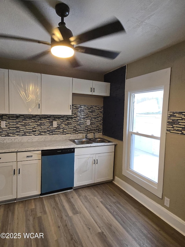 kitchen featuring sink, dishwashing machine, hardwood / wood-style flooring, decorative backsplash, and white cabinets