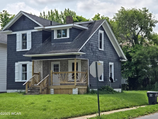 931 Richie Ave, Lima, OH 45805 - view of front facade featuring covered porch, a chimney, a front yard, a shingled roof, and stone siding