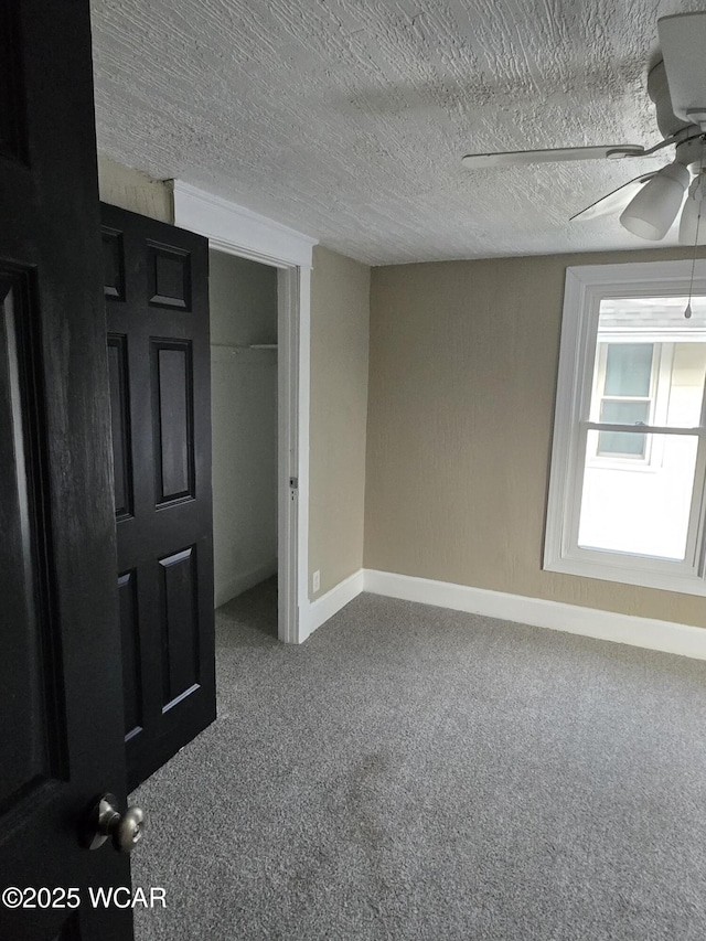 carpeted empty room featuring ceiling fan and a textured ceiling