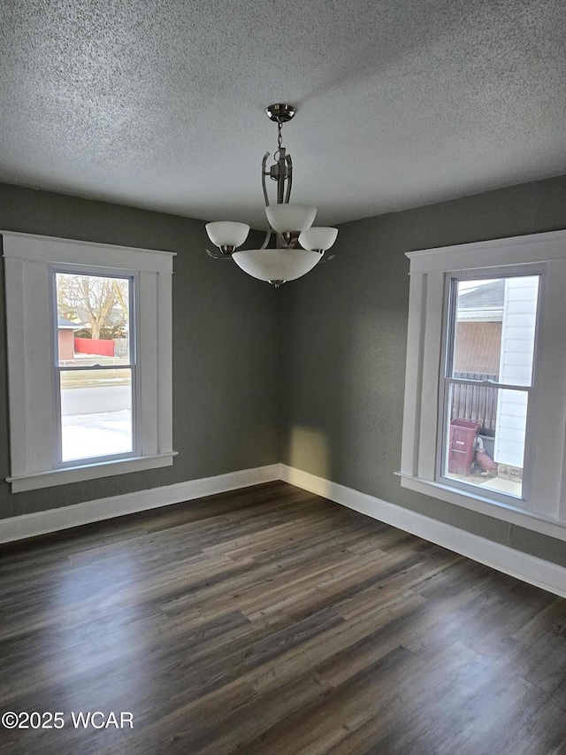 unfurnished dining area with plenty of natural light, dark hardwood / wood-style floors, and a textured ceiling