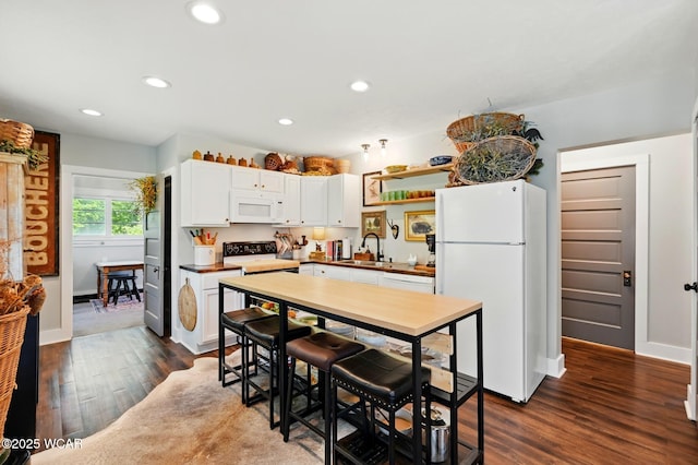 219 N Market St, Kenton, OH 43326 - kitchen with white appliances, dark wood-style flooring, white cabinets, a sink, and baseboards