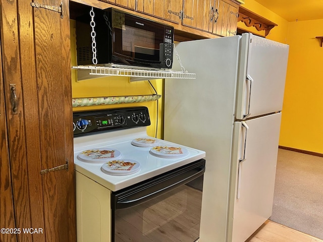 1440 Southwood Dr, Lima, OH 45805 - kitchen featuring electric stove, freestanding refrigerator, black microwave, brown cabinetry, and light carpet