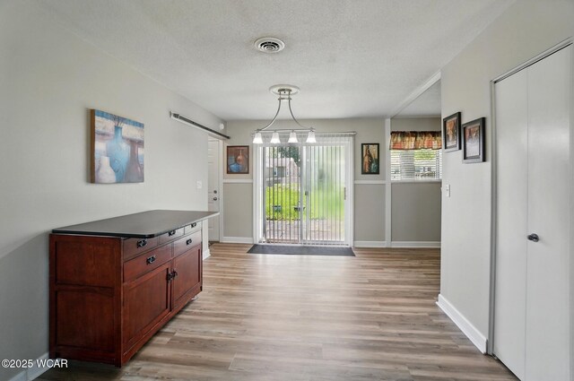 2911 Lakewood Ave, Lima, OH 45805 - unfurnished dining area featuring a barn door, light wood-style flooring, baseboards, and a textured ceiling