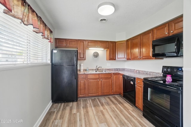 2911 Lakewood Ave, Lima, OH 45805 - kitchen featuring black appliances, a sink, brown cabinets, and light wood-style flooring