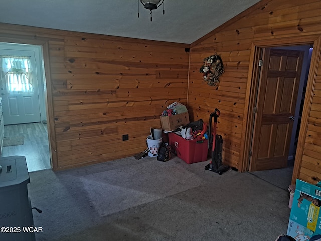 interior space with wood walls, carpet, and vaulted ceiling