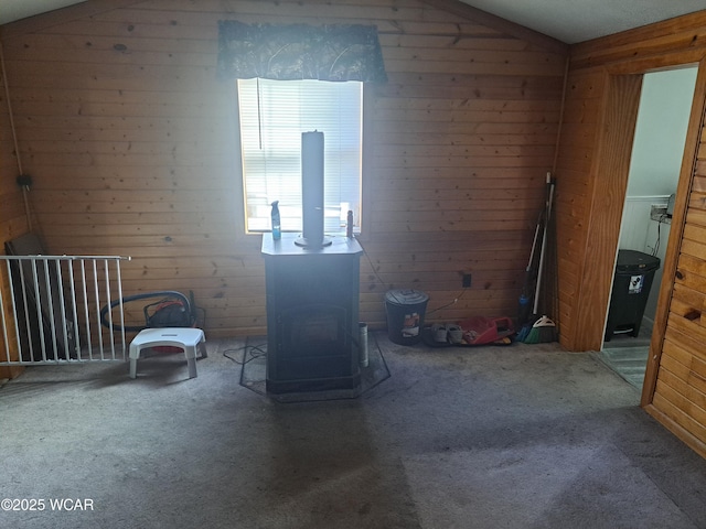 interior space with lofted ceiling, wooden walls, and a wood stove