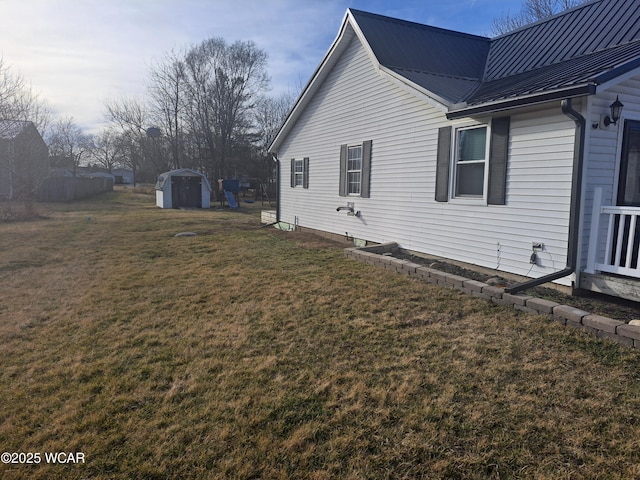 view of side of home featuring a storage unit, a lawn, metal roof, and an outdoor structure