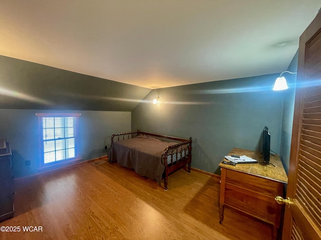 bedroom featuring baseboards, vaulted ceiling, and wood finished floors