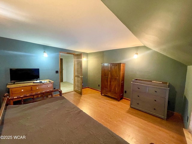 bedroom with light wood-type flooring and vaulted ceiling