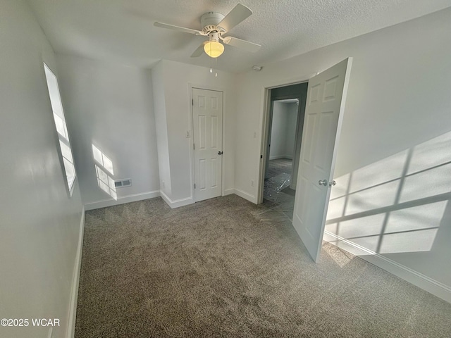 unfurnished bedroom with a textured ceiling, carpet flooring, and ceiling fan