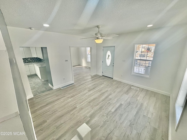 entryway with light hardwood / wood-style floors, ceiling fan, and a textured ceiling