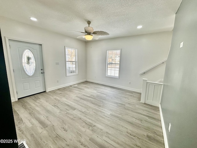 foyer entrance with ceiling fan, light hardwood / wood-style flooring, and a textured ceiling