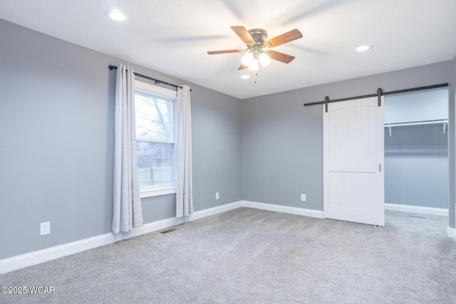 1758 W Hume Rd, Lima, OH 45806 - unfurnished bedroom with ceiling fan, a barn door, a closet, and light carpet