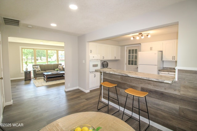4945 New Haven Dr, Lima, OH 45806 - kitchen featuring white appliances, recessed lighting, white cabinets, a breakfast bar, and a peninsula