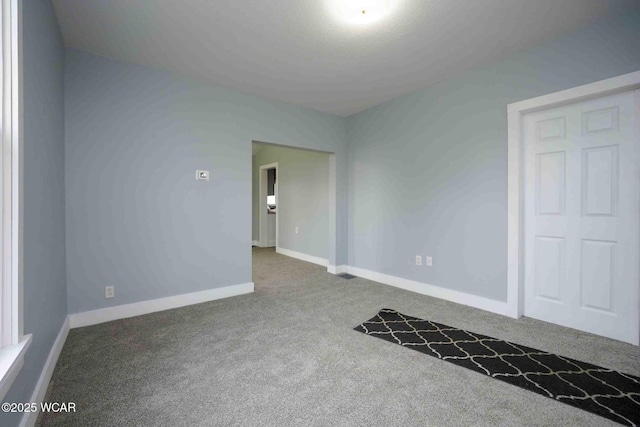 empty room featuring carpet and baseboards