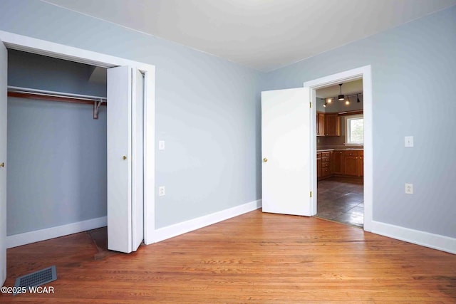 unfurnished bedroom with baseboards, visible vents, and wood finished floors