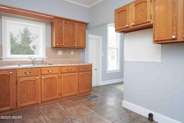 kitchen with crown molding, light countertops, a sink, and brown cabinets