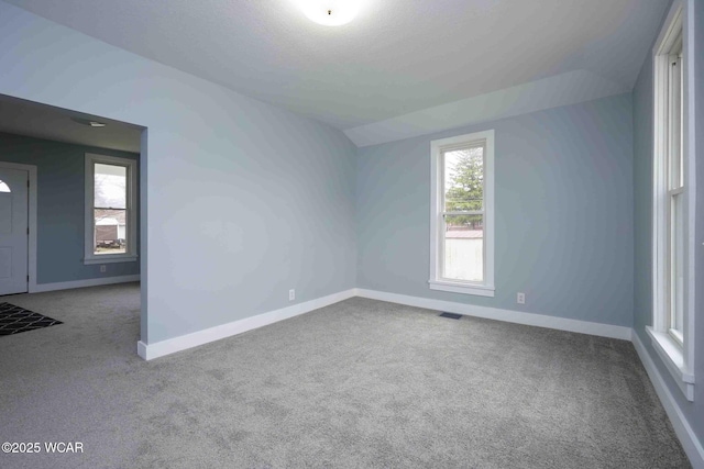 spare room with carpet floors, baseboards, and visible vents