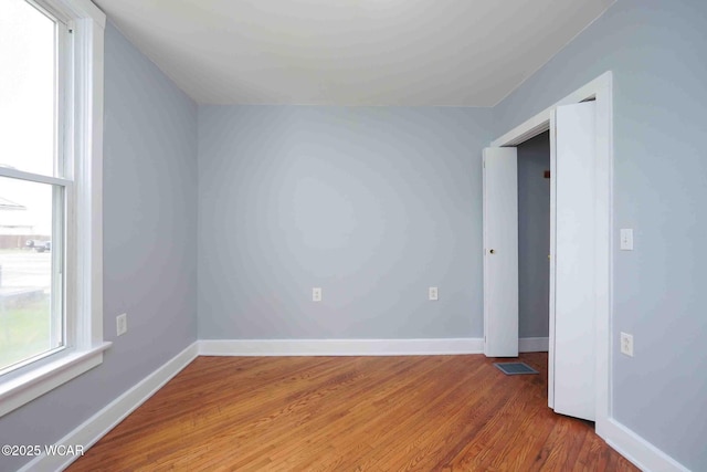 unfurnished room featuring visible vents, baseboards, and wood finished floors