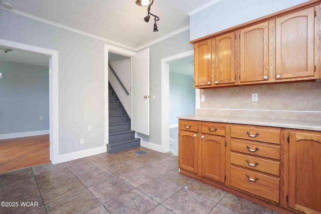 kitchen featuring light countertops, ornamental molding, baseboards, backsplash, and brown cabinetry