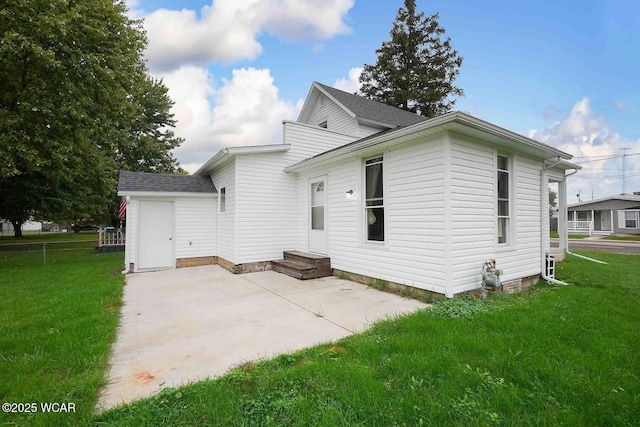 back of house with roof with shingles, a yard, and a patio area