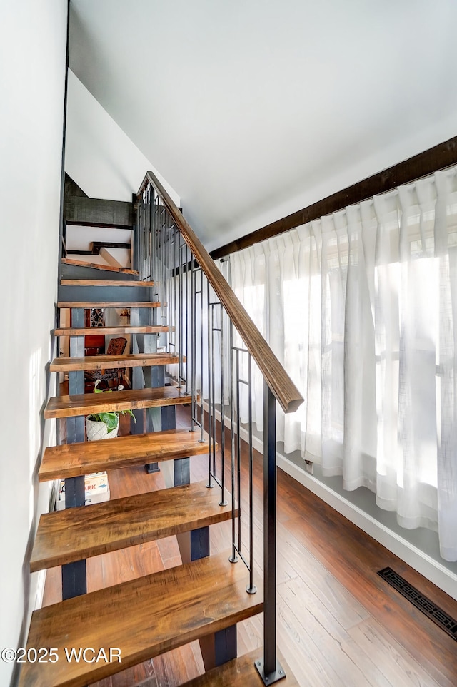 stairs with visible vents and hardwood / wood-style floors