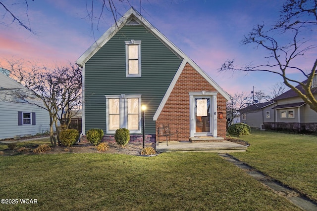 back of property with a yard and brick siding