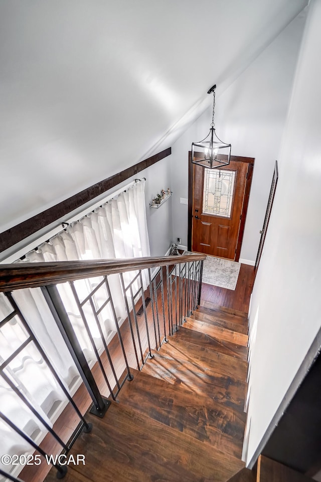 stairs with a notable chandelier, lofted ceiling, and hardwood / wood-style floors