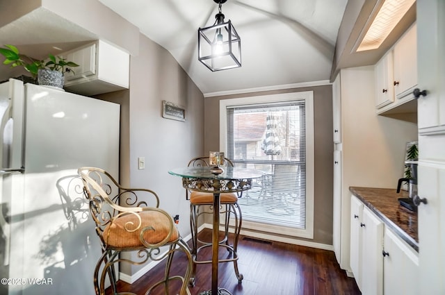 dining room featuring dark wood finished floors, vaulted ceiling, and baseboards