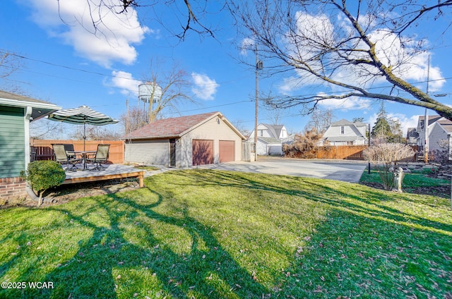 view of yard with an outbuilding, a wooden deck, a detached garage, and fence