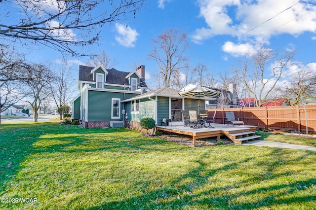 rear view of house with a wooden deck, a lawn, and fence