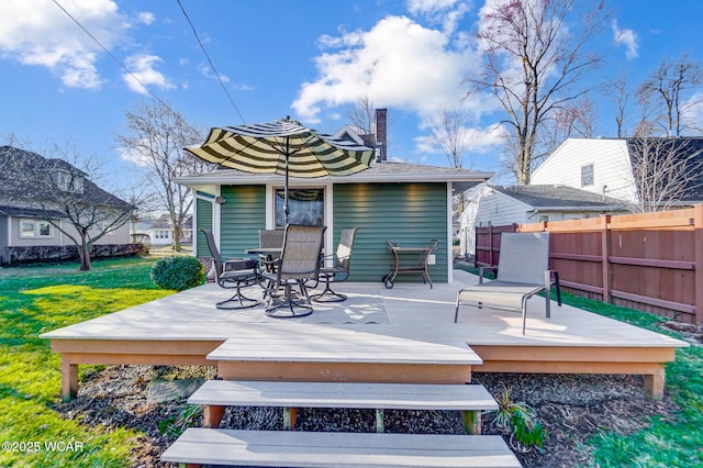 wooden deck with outdoor dining area, a yard, and fence