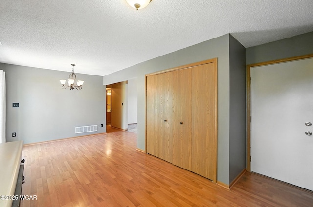 807 Centerfield Dr, Paulding, OH 45879 - unfurnished bedroom featuring light wood-style flooring, a chandelier, a closet, and a textured ceiling