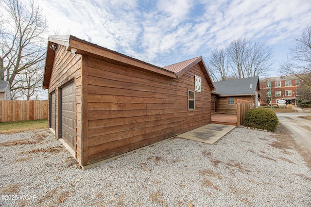 view of property exterior featuring a garage, a deck, and fence