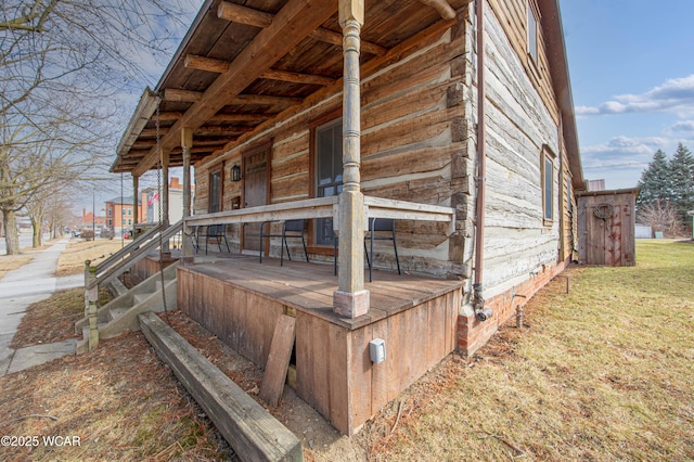 wooden deck featuring a porch and a lawn