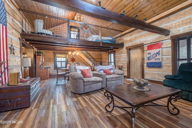 living room with beam ceiling, a towering ceiling, wood finished floors, a chandelier, and wooden ceiling