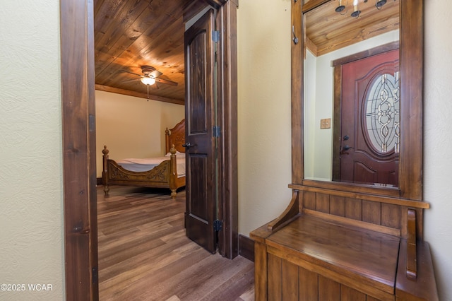 entryway with wood ceiling, baseboards, wood finished floors, and a textured wall