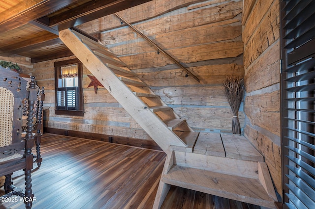 stairs featuring beam ceiling, wooden walls, and wood finished floors