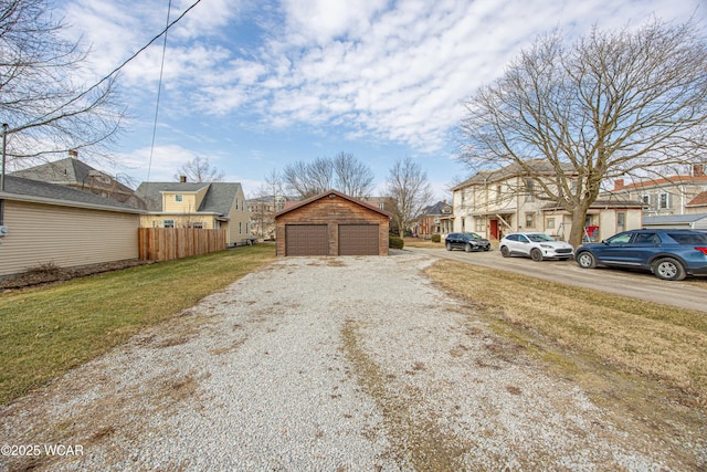 exterior space with a garage, a residential view, fence, and an outbuilding