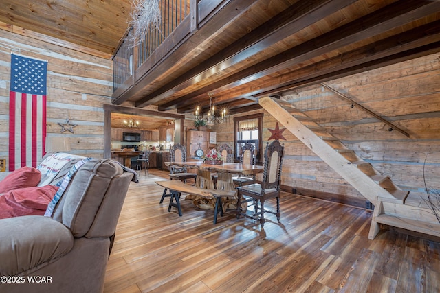 dining area featuring wood walls, an inviting chandelier, wood finished floors, and beamed ceiling