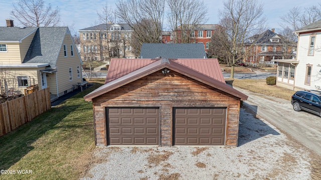 garage featuring driveway, a residential view, and fence