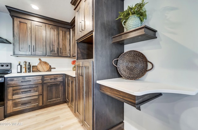 kitchen with dark brown cabinetry, range, extractor fan, and light hardwood / wood-style flooring