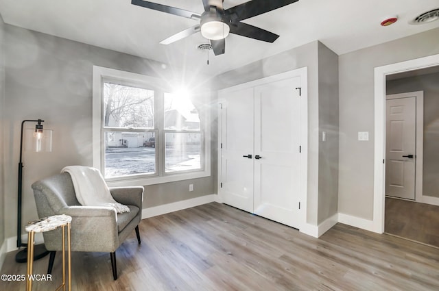 sitting room with ceiling fan and light wood-type flooring