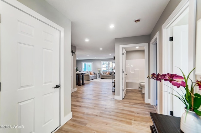 corridor featuring a barn door and light hardwood / wood-style flooring