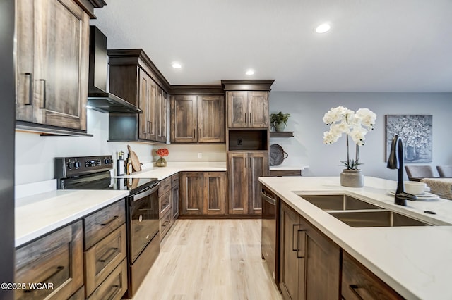 kitchen featuring sink, dark brown cabinetry, black appliances, light wood-type flooring, and wall chimney exhaust hood