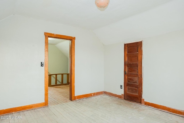 additional living space featuring lofted ceiling and light hardwood / wood-style flooring